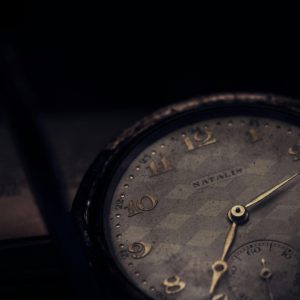 pexels-photo-1034425-1034425 Close-up of a vintage pocket watch with a textured dial in a moody setting.